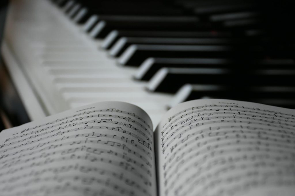 A focused view on sheet music with blurred piano keys in the background.